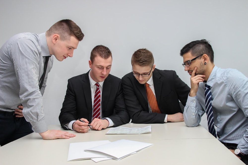 Four colleagues in business attire reviewing documents together at a table
